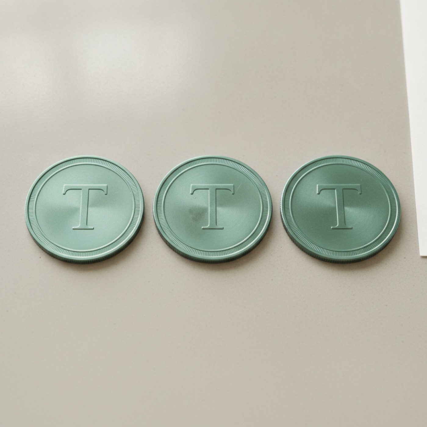 Three identical Tether coins standing in a row on a light background